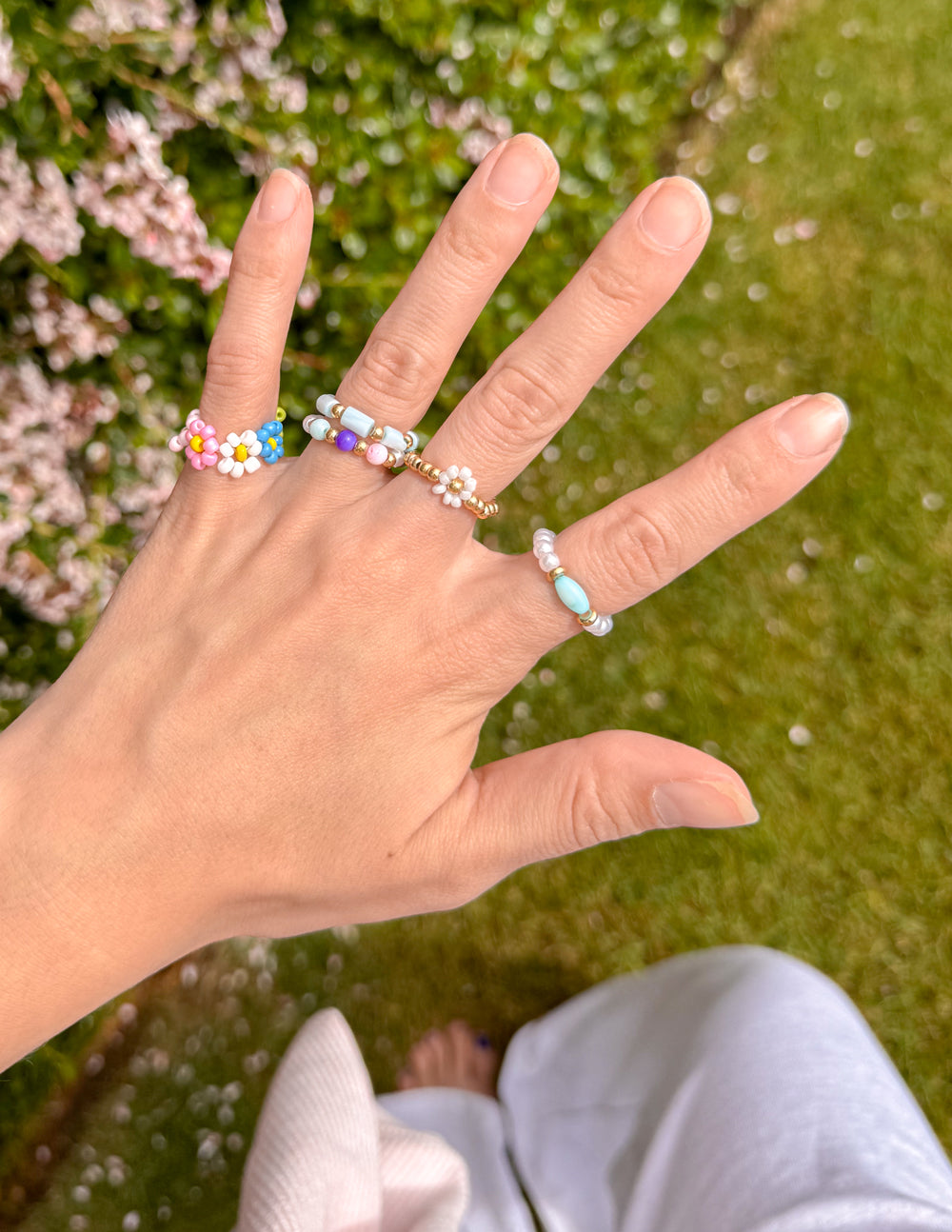 Colorful Elevated Faith Christian Jewelry rings displayed on a hand outdoors with greenery