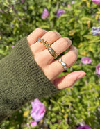 Elevated Faith Christian Jewelry featuring gold and white rings on a hand with green sweater outdoors