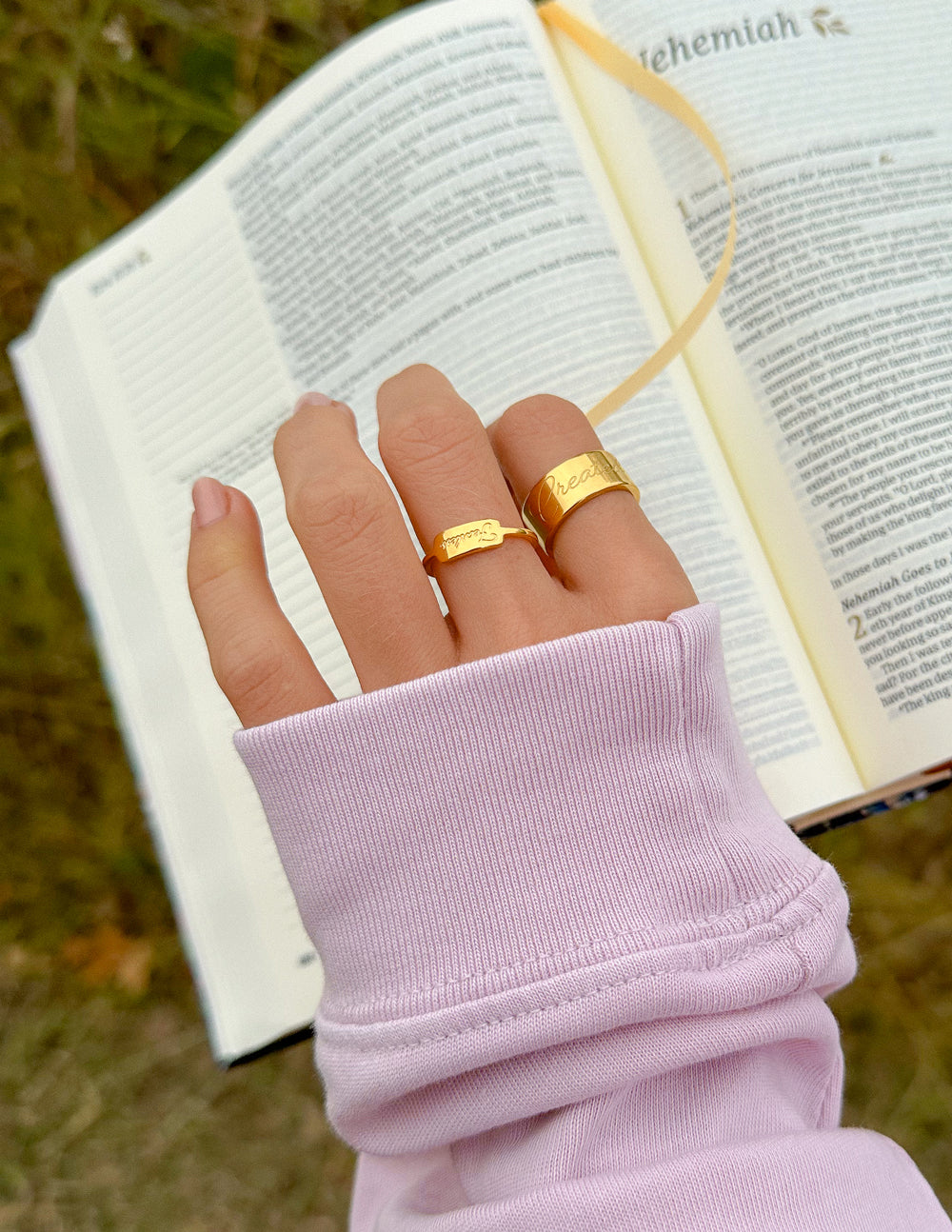 Gold Elevated Faith Ring held over an open Bible, symbolizing faith in Christian Jewelry