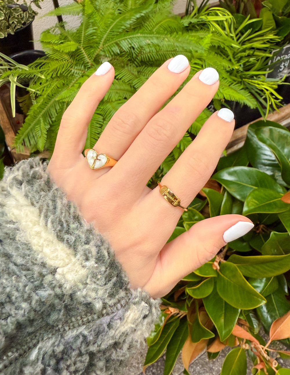 Hand wearing a gold ring with a heart design, featuring Christian Jewelry from Elevated Faith
