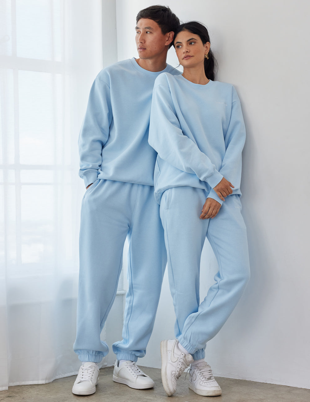 Two models wearing matching light blue Christian Crewneck Sweatshirt and sweatpants for a comfortable look
