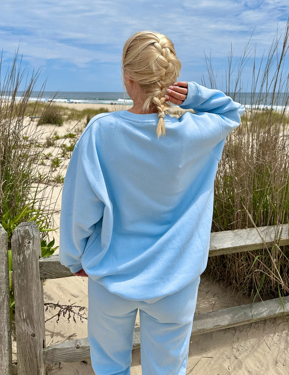Woman wearing Elevated Faith Christian Crewneck Sweatshirt in light blue by the beach