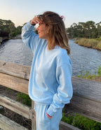 Woman wearing a light blue Christian Crewneck Sweatshirt by Elevated Faith near a scenic river