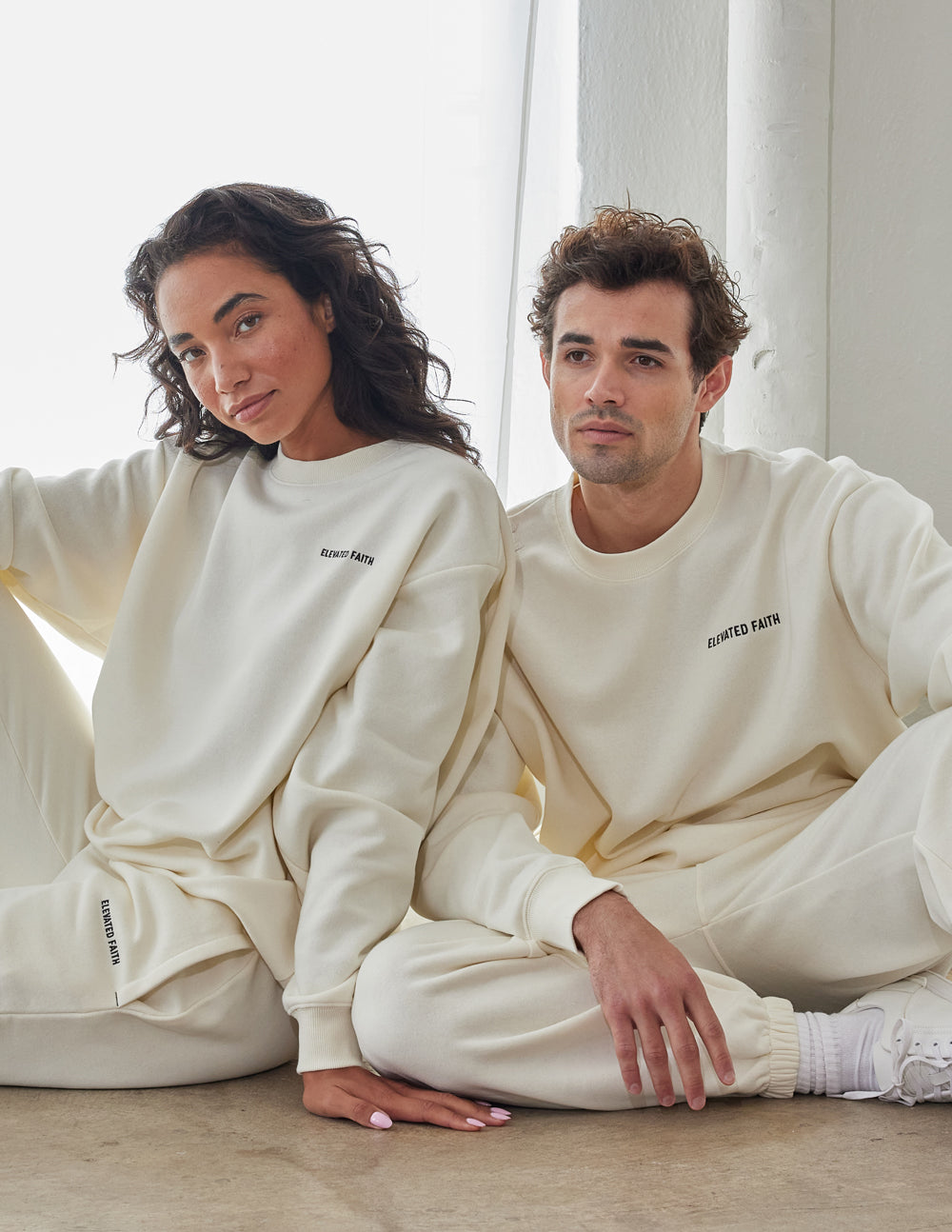 Couple wearing Elevated Faith Christian Crewneck Sweatshirt in a cozy setting, showcasing comfort and style
