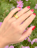 Gold Elevated Faith Ring shown on a hand, surrounded by pink flowers, ideal Christian Jewelry piece