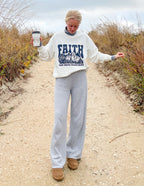 Woman wearing a white Christian Crewneck Sweatshirt with graphic text, styled casually outdoors