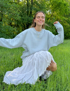 Woman wearing a light blue Christian Crewneck Sweatshirt with a smile in a grassy field