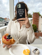 Elevated Faith Christian iPhone Case featuring the message God is Always With Me while holding pastry and fruit