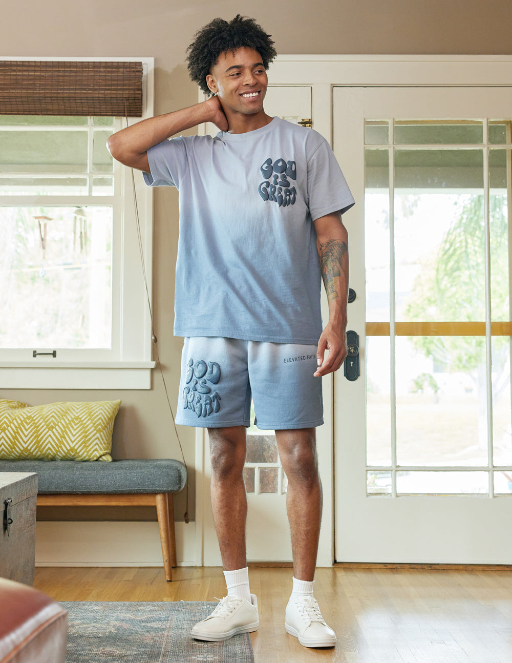 Man wearing Elevated Faith Christian Shorts with matching ombre t-shirt in a bright living room setting
