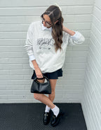 Elevated Faith Christian Crewneck Sweatshirt in light gray with text graphic, styled with a skirt and handbag