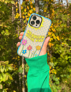 Colorful Christian iPhone Case featuring 'Growing with God' design with flowers and sun in a natural setting