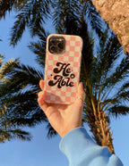 Christian iPhone Case with a pink checker pattern and the phrase He Able on it outdoors
