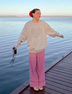 Woman wearing a beige Christian Crewneck Sweatshirt with a heart design by Elevated Faith beside water