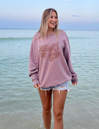 Woman wearing a Christian Crewneck Sweatshirt with 'Heart of God' design by Elevated Faith at the beach