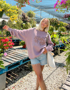 Elevated Faith Christian Crewneck Sweatshirt in dusty pink worn by a woman in a floral garden
