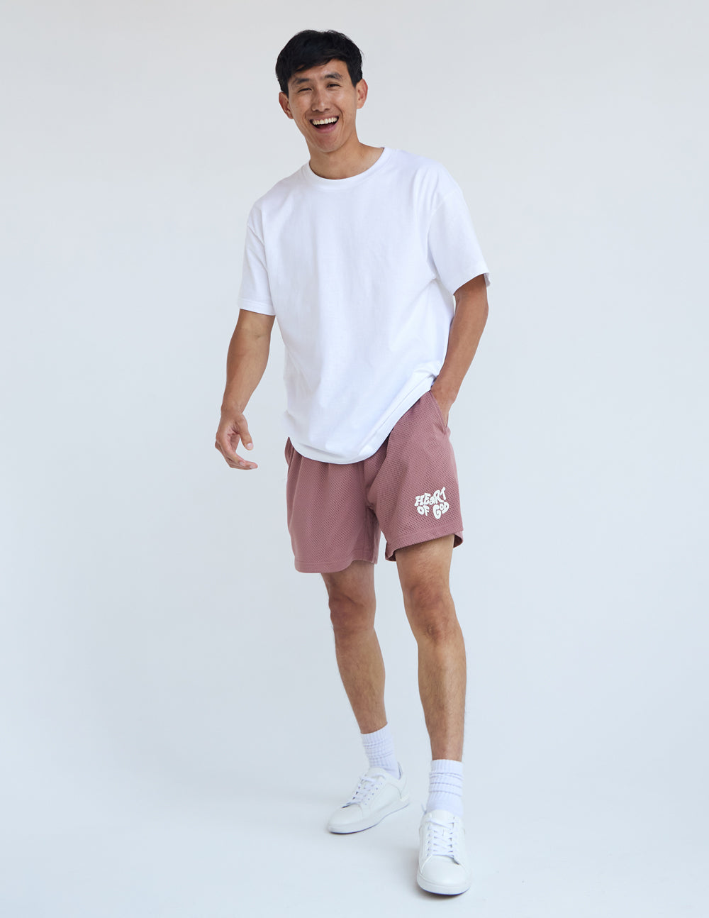 Male model wearing pink Christian Shorts from Elevated Faith with a white t-shirt and sneakers