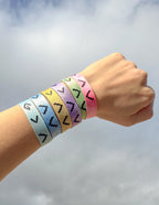 Colorful Elevated Faith Christian Jewelry Bracelet wristbands displayed on a hand against a cloudy sky
