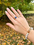 Elevated Faith Christian Jewelry Ring on hand with a blue stone surrounded by autumn leaves