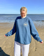 Model wearing Elevated Faith Christian Crewneck Sweatshirt in blue by the beach on a sunny day