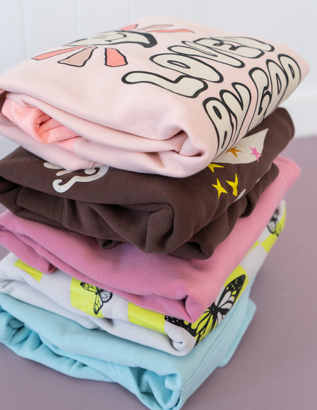 Stack of colorful Christian Crewneck Sweatshirts in various designs and colors folded neatly