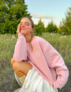 Model wearing a pink Christian Crewneck Sweatshirt in a natural outdoor setting