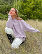 Woman posing in a light purple Christian Crewneck Sweatshirt with the phrase 'Peace of God' in a natural setting