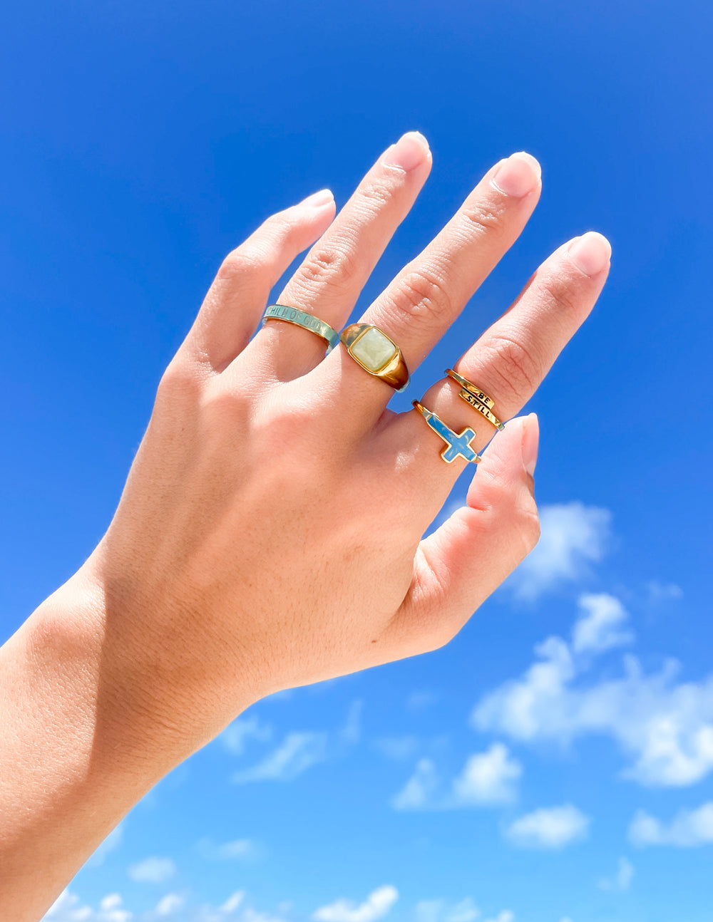 Elevated Faith Christian Jewelry rings displayed on a hand against a bright blue sky