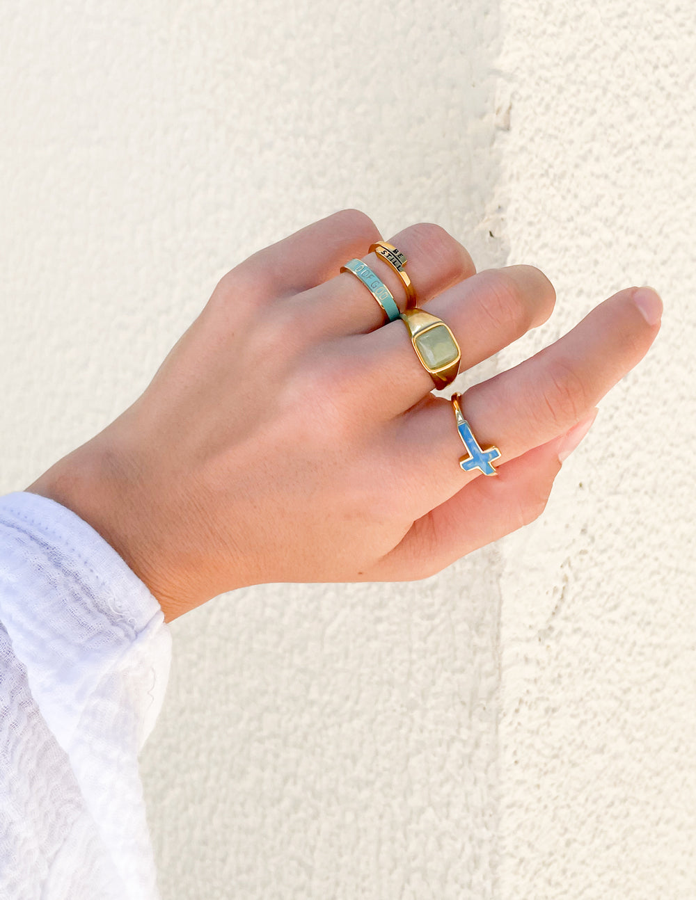 Hand wearing Elevated Faith Christian Jewelry rings featuring a turquoise stone and a cross design