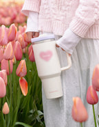 Elevated Faith Christian Gifts Tumbler with a heart design and straw, among pink tulips