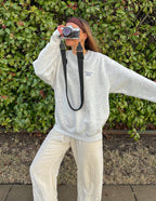 Woman wearing a gray Christian Crewneck Sweatshirt with relaxed fit, posing outdoors with a camera