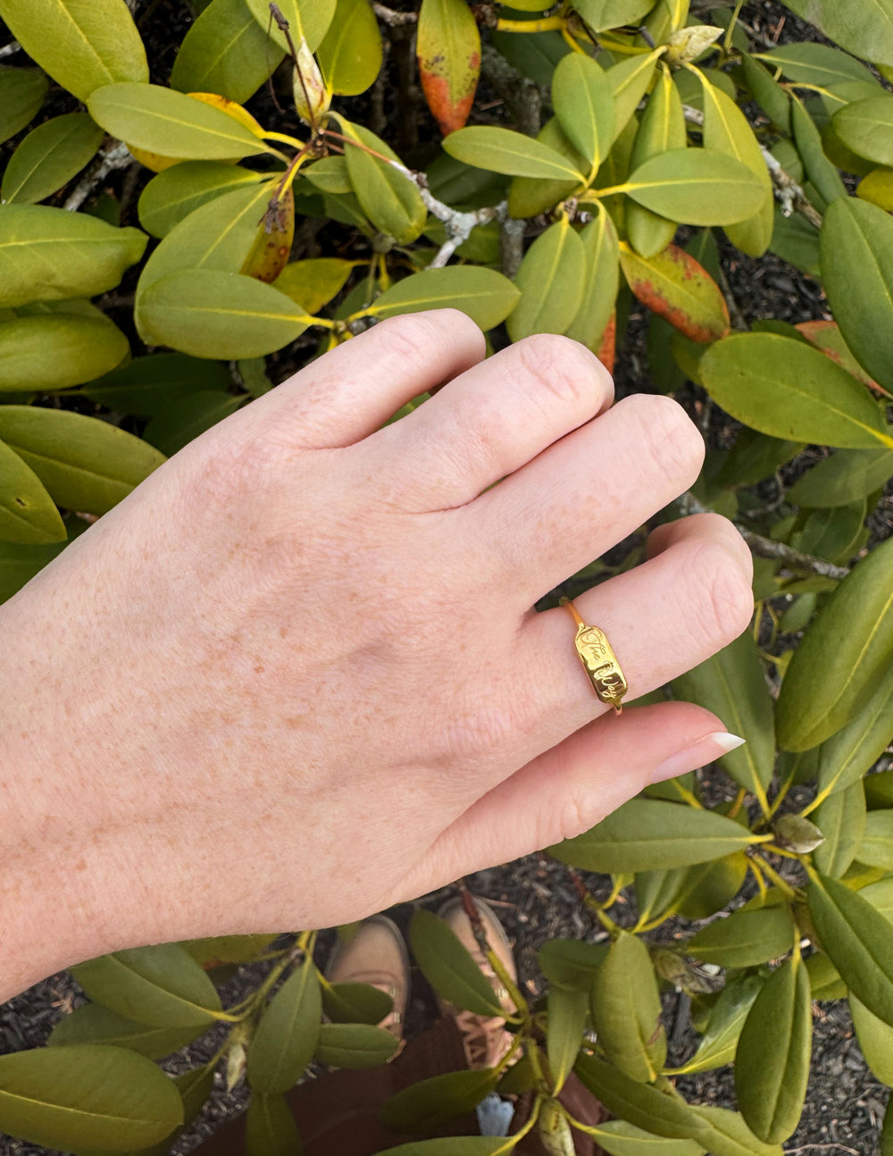 Elevated Faith Gold Ring on Hand Among Green Leaves, Perfect for Christian Jewelry Enthusiasts