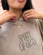 Elevated Faith Christian Jewelry Necklace with delicate charms worn on a brown hoodie