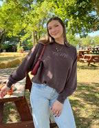 Casual woman wearing a Christian Crewneck Sweatshirt in brown with YHWH lettering outdoors
