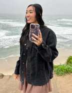Woman holding a Christian iPhone Case by Elevated Faith while standing by the beach