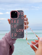 Elevated Faith Christian iPhone Case with pink lettering saying You Are So Loved and a beaded strap