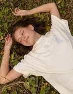 Model lying on the ground wearing a cream Elevated Faith Christian Apparel T-Shirt with inspirational text