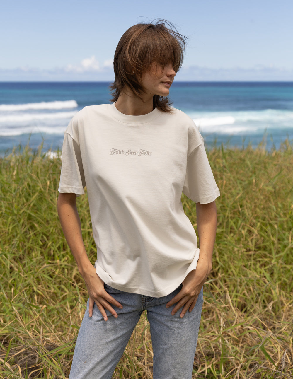 Elevated Faith Christian Apparel T-Shirt in light beige against a beach background