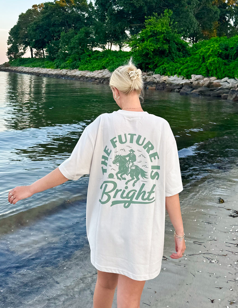 Elevated Faith Christian Apparel T-Shirt with 'The Future is Bright' design on back, worn on a beach