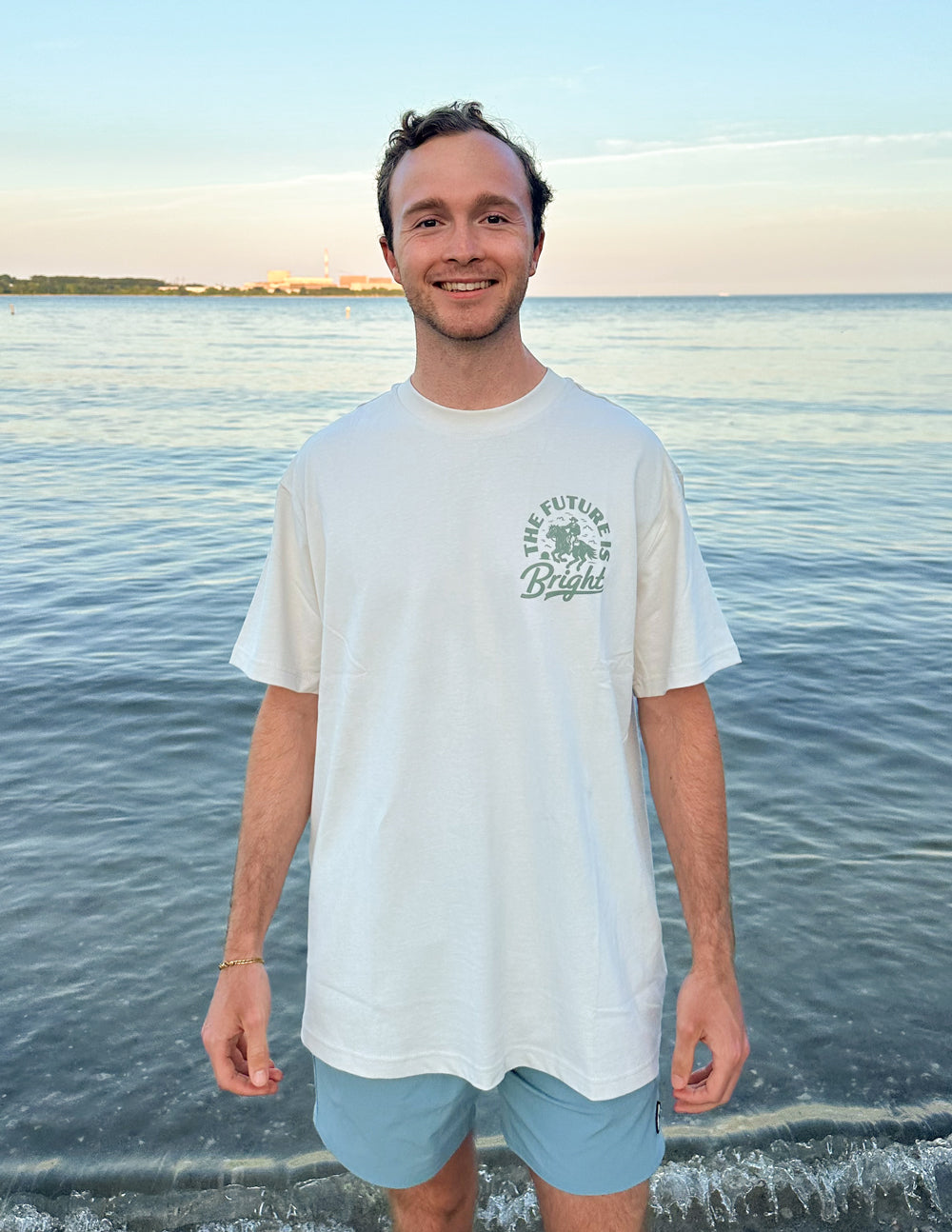 Elevated Faith Christian Apparel T-Shirt in white with uplifting graphic, worn by model at beach