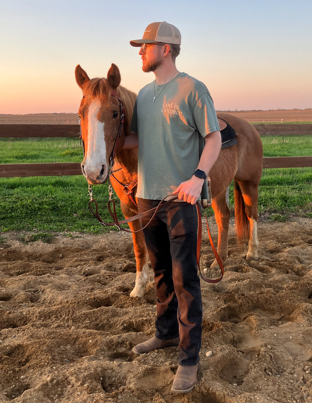 Man wearing Elevated Faith Christian Apparel T-Shirt while standing next to a horse at sunset