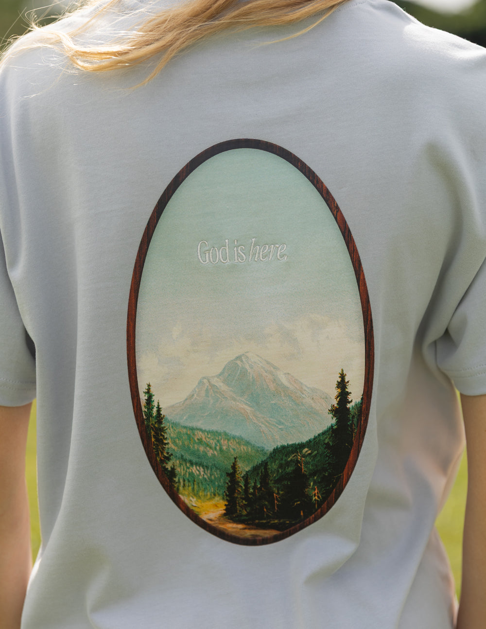 Elevated Faith Christian Apparel T-Shirt featuring a serene mountain landscape and the phrase God is here