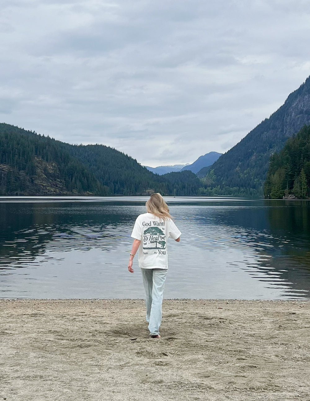 Woman wearing a Christian Apparel T-Shirt from Elevated Faith walking by a serene lake