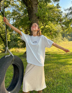 Woman wearing a light gray Christian Apparel T-Shirt, enjoying outdoor scenery with a tire swing