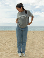 Woman wearing Elevated Faith Christian Apparel T-Shirt in gray with kingdom print on the beach