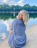 Model wearing Elevated Faith Christian Apparel T-Shirt with Living Water graphic by the lake