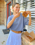 Woman wearing a casual Elevated Faith Christian Apparel T-Shirt while enjoying a cinnamon roll outdoors