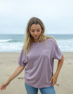 Elevated Faith Christian Apparel T-Shirt in lavender with 'Peace of God' graphic on the beach