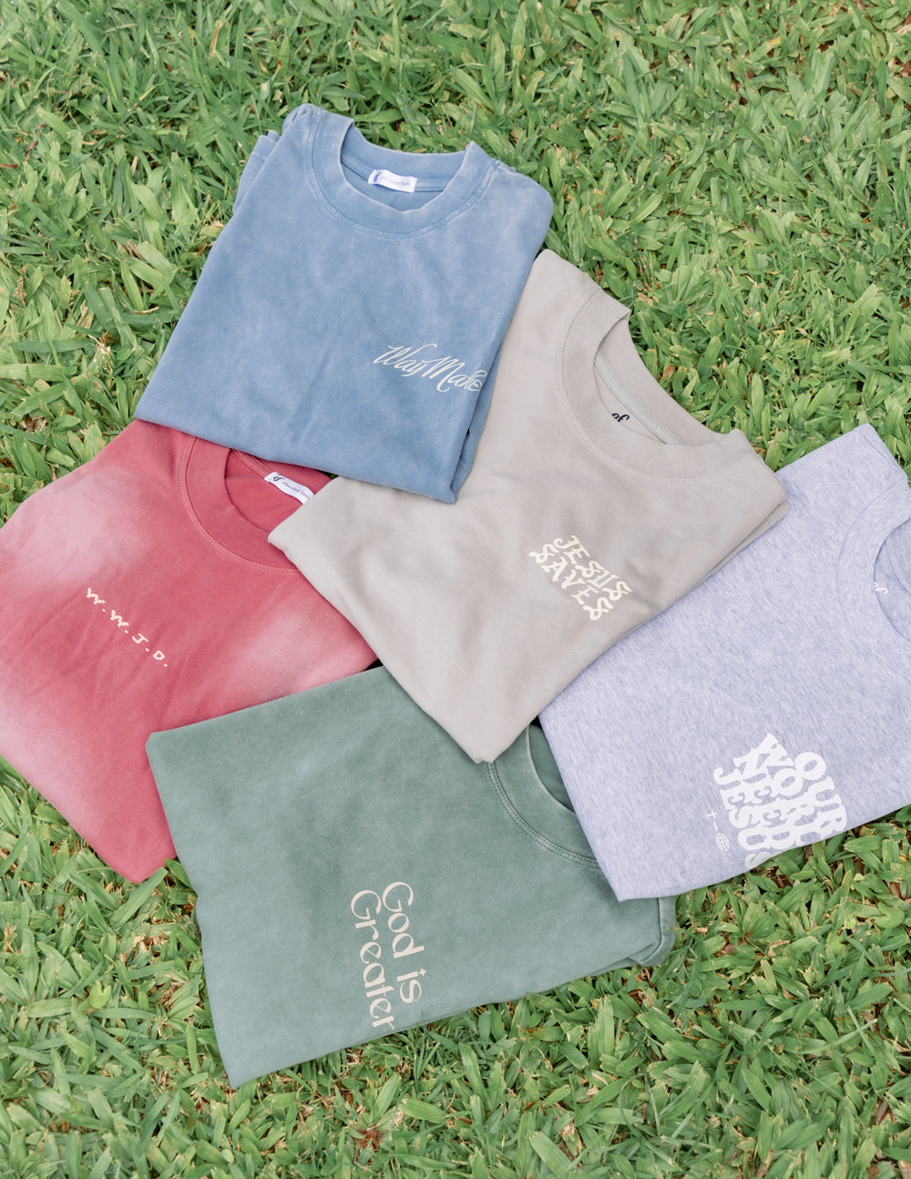 Collection of Elevated Faith Christian Apparel T-Shirt in various colors and designs on green grass