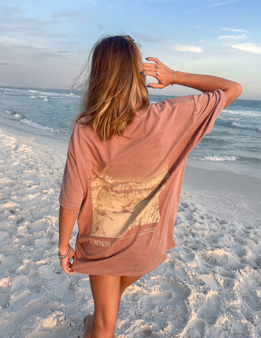 Woman wearing Elevated Faith Christian Apparel T-Shirt with a beach background and inspirational graphics