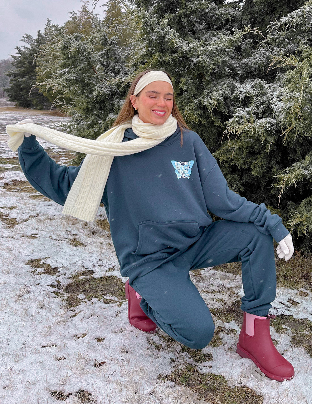 Woman in a navy Christian Hoodie with butterfly design, styled with a white scarf and winter attire